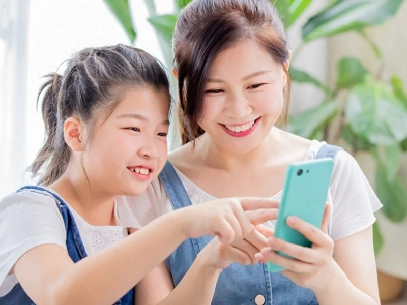 Một trader trẻ tuổi đang sử dụng điện thoại di động để theo dõi thị trường và thực hiện giao dịch